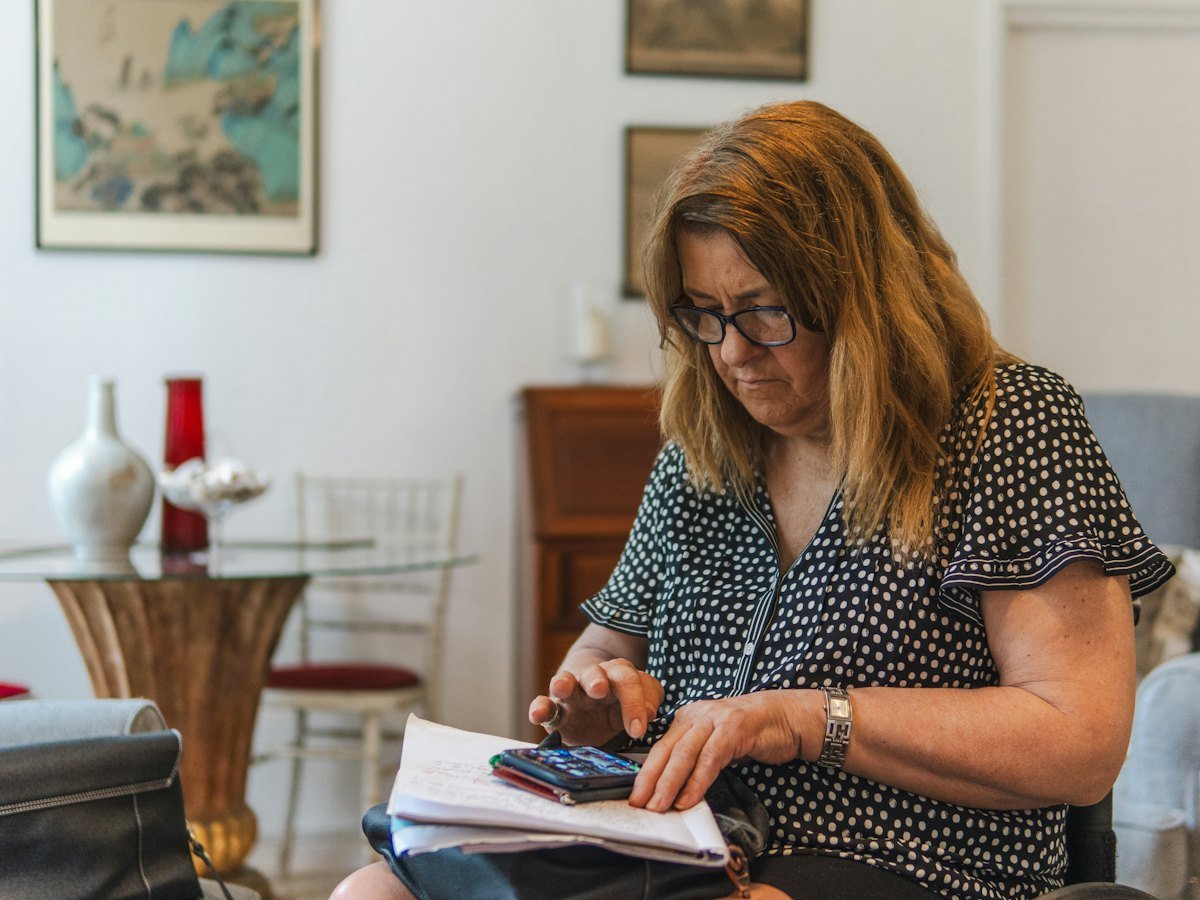 A woman working through bills with a calculator at her table