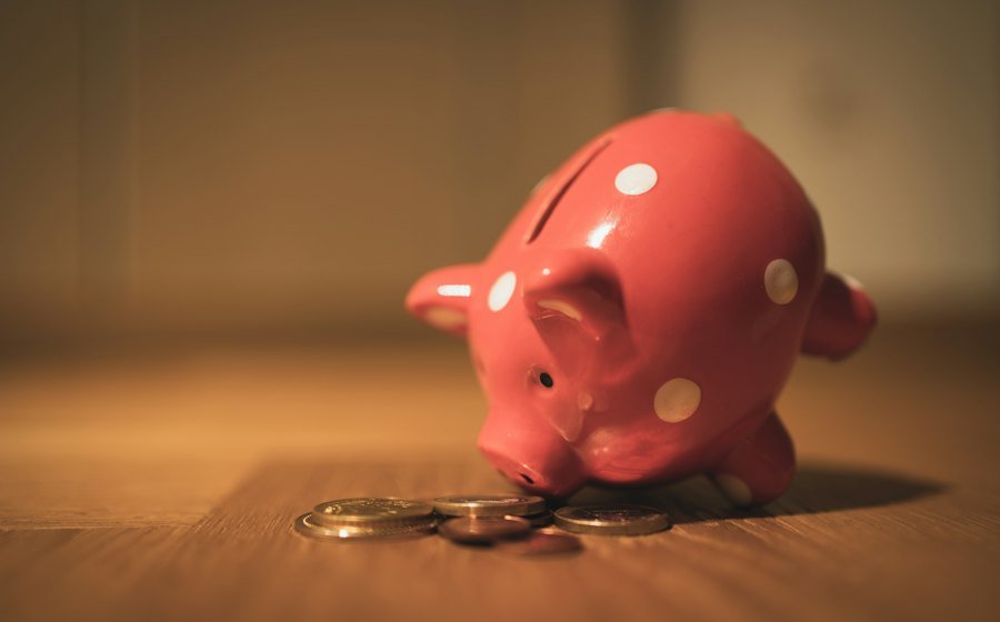 A piggy bank with coins on a wooden table