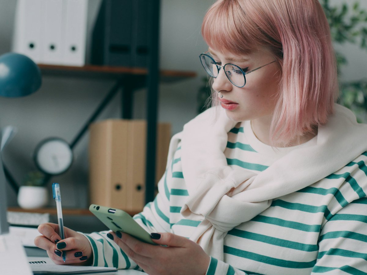 A woman at her desk checking her phone