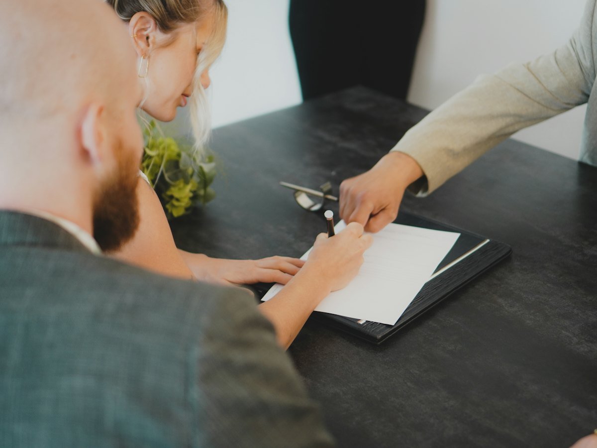 A couple signing a document together at a desk