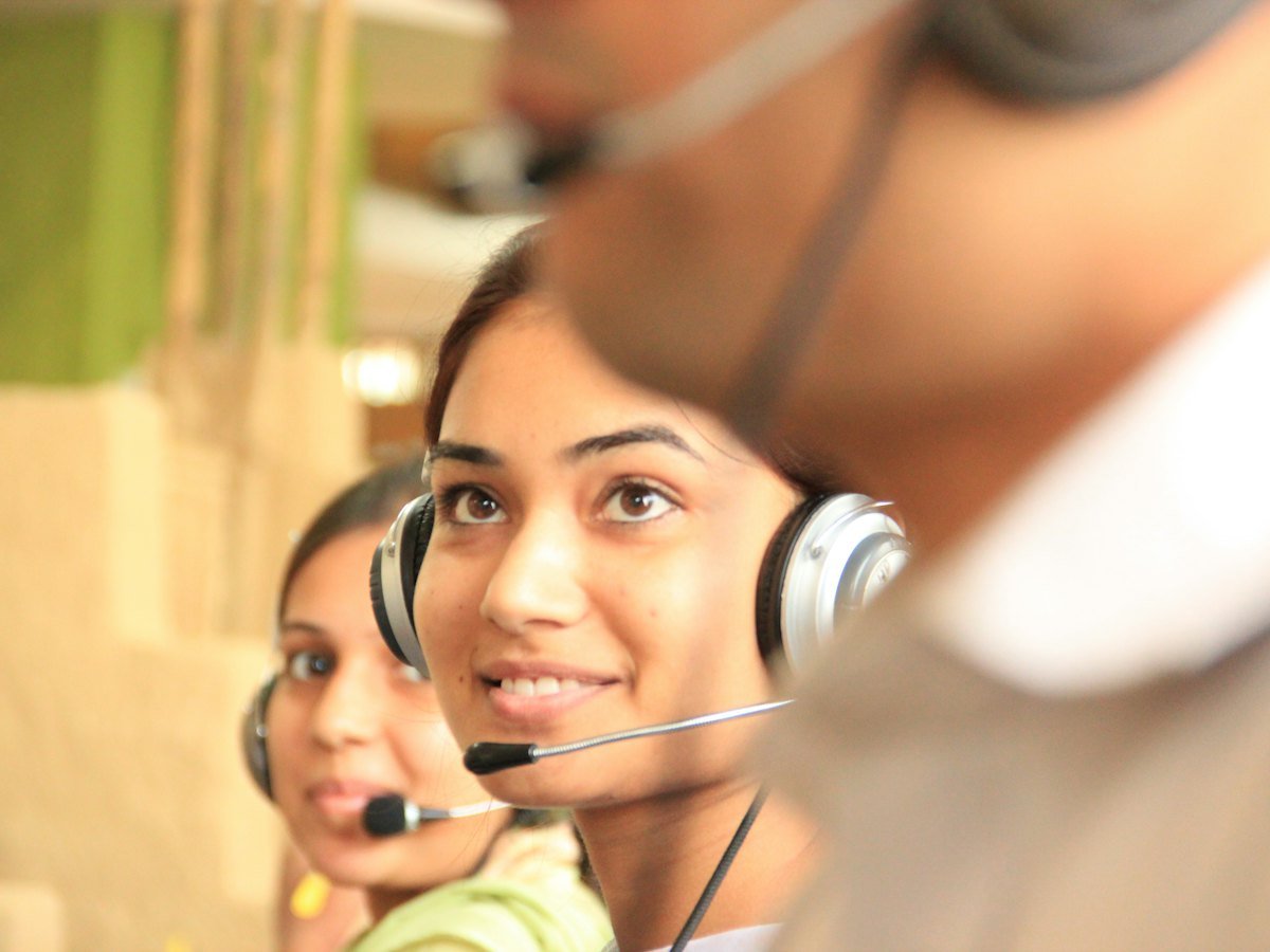 Two support specialists wearing headsets in a bright office